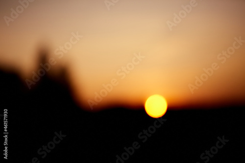 Unfocused blured multicolored background bokeh of sunset. The sun is on the horizon. Orange color of the sky. It is getting dark. The last rays. Blurry silhouette. Abstract wallpaper. Abstraction