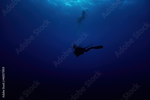 Woman scuba diver silhouette swimming in deep blue