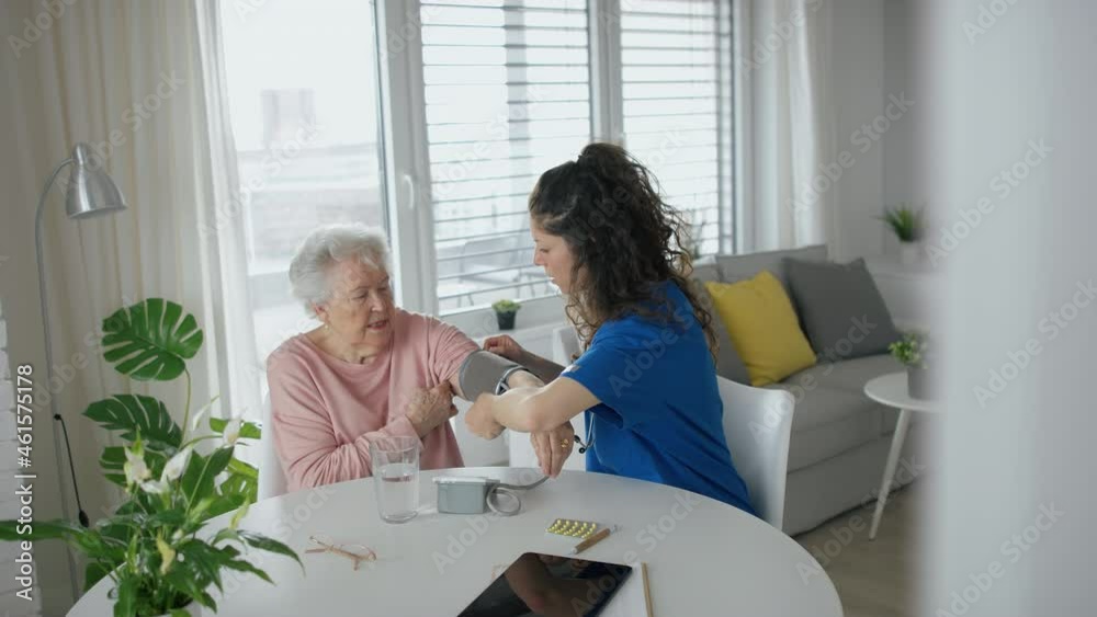 Healthcare worker or caregiver visiting senior woman indoors at home, measuring her blood pressure. Healthcare worker or caregiver visiting senior woman indoors at home, measuring her blood pressure.