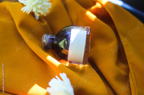 50 ml Perfume bottle with blank white label on textured orange fabric background. Perfume bottle stock photo