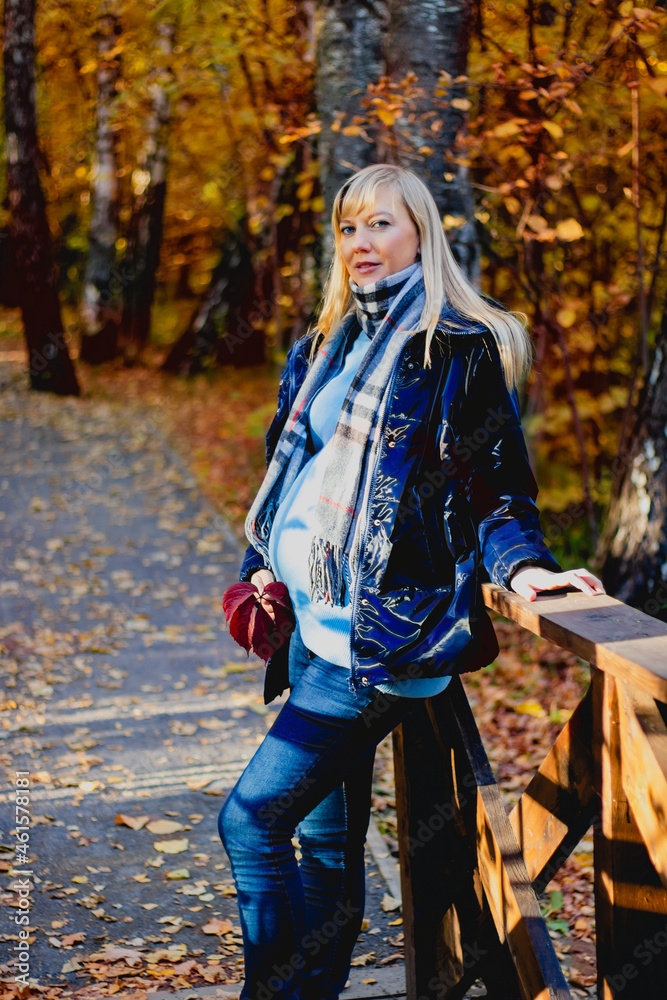 A young beautiful smiling pregnant woman in a warm knitted outfit on a cozy autumn walk, a lifestyle in the fresh air. A young beautiful smiling pregnant woman in a warm knitted outfit on a cozy autumn walk, a lifestyle in the fresh air.