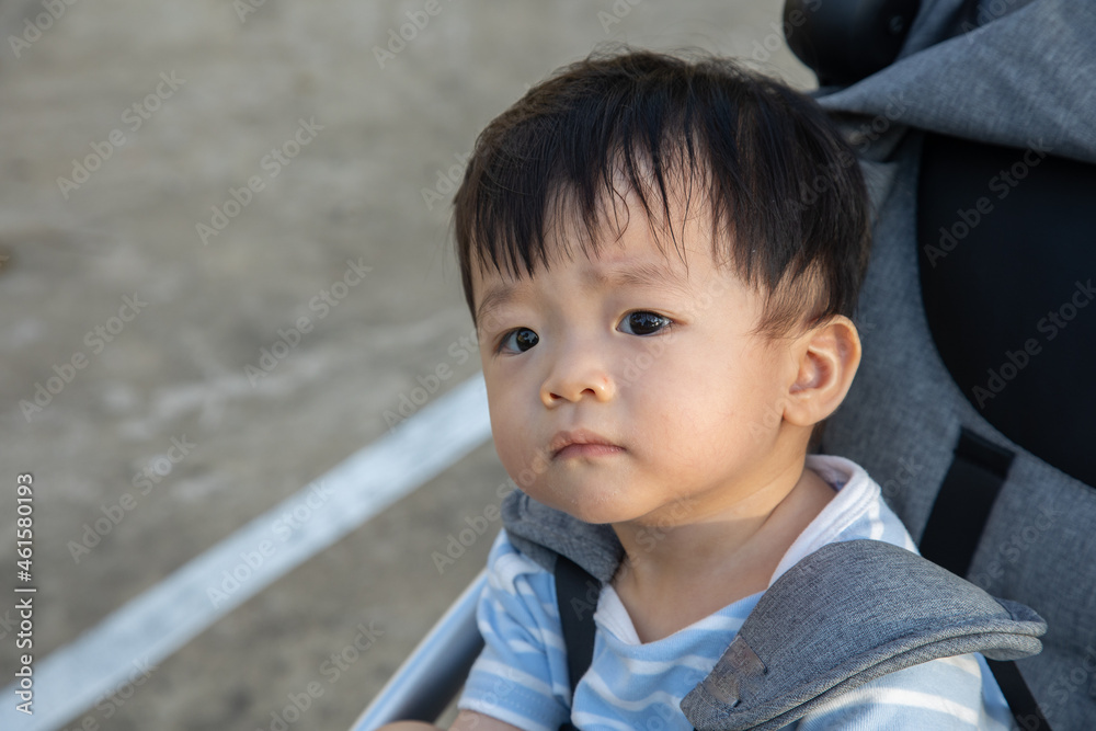 portrait image of Happy and cute Asian Chinese baby boy sitting on stroller at park during evening