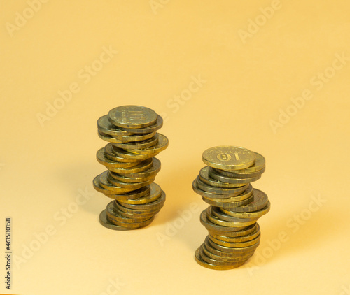 Two turrets made of coins. Money on yellow background photo