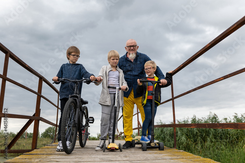 dad and children went for walk around village on bicycles and scooters photo