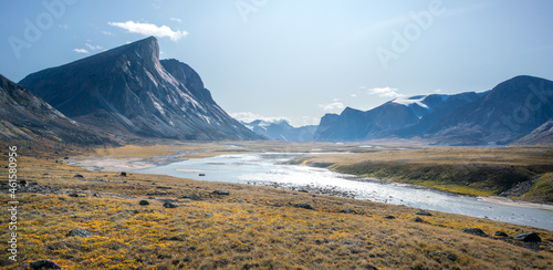 Wild Owl River winds through remote arctic landscape in Akshayuk Pass, Baffin Island, Canada. Moss valley floor and dramatic cliffs. Sunny day of arctic summer in remote wilderness far north. photo