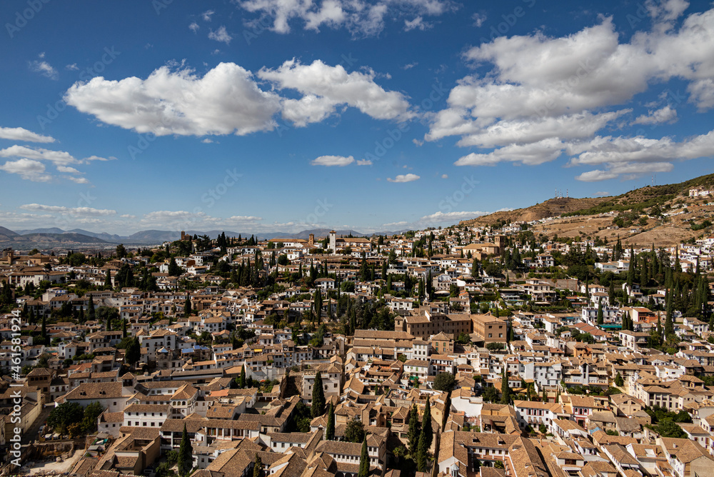 Panorama of the Albaicín, the historic city center of Granada with its characteristic white houses under a picturesque cloudy blue sky, seen from the Alhambra, Andalusia, Spain