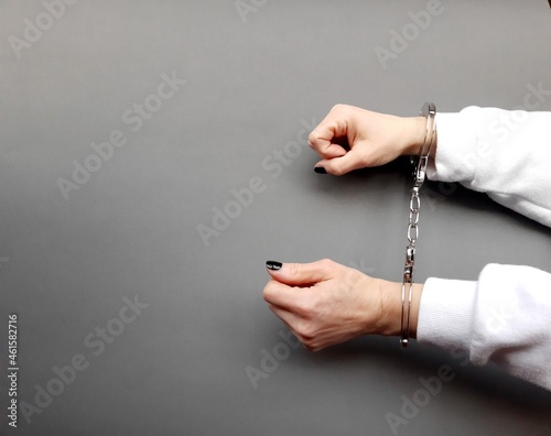 An arrested woman in handcuffs on a gray background. photo