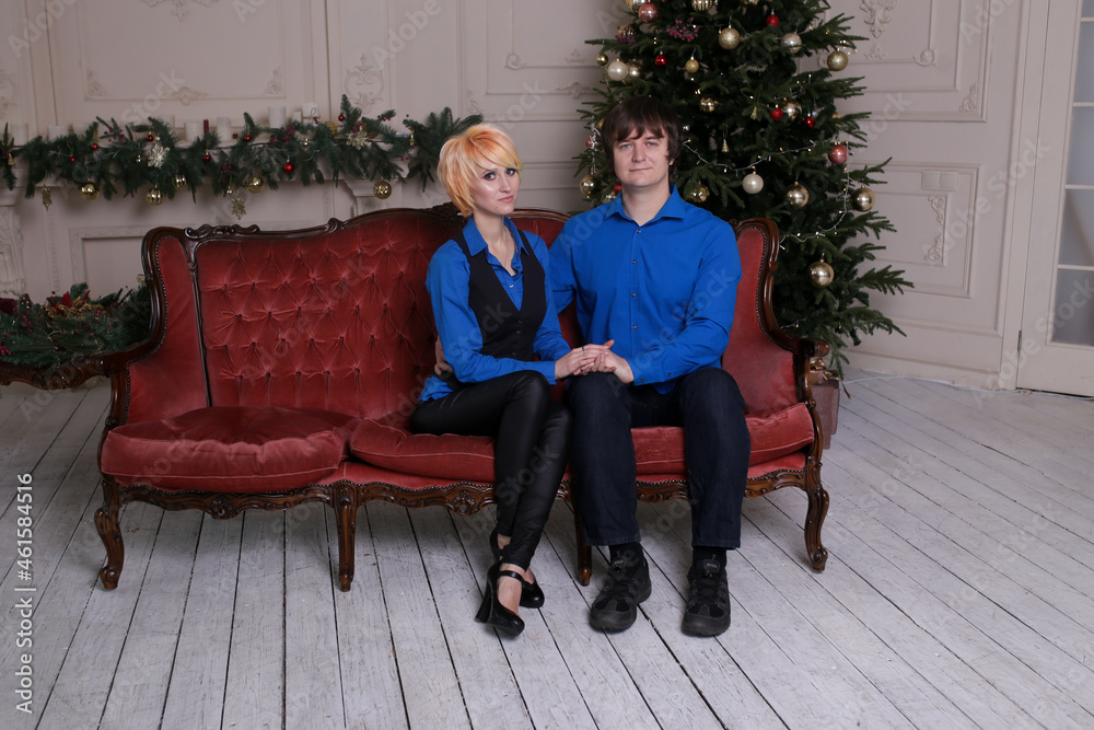 Obraz premium Beautiful couple sitting on sofa next to a nicely decorated Christmas tree