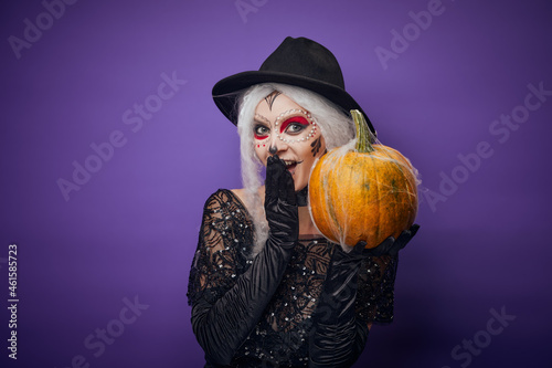Cheerful young woman with Halloween make-up and pumpkin