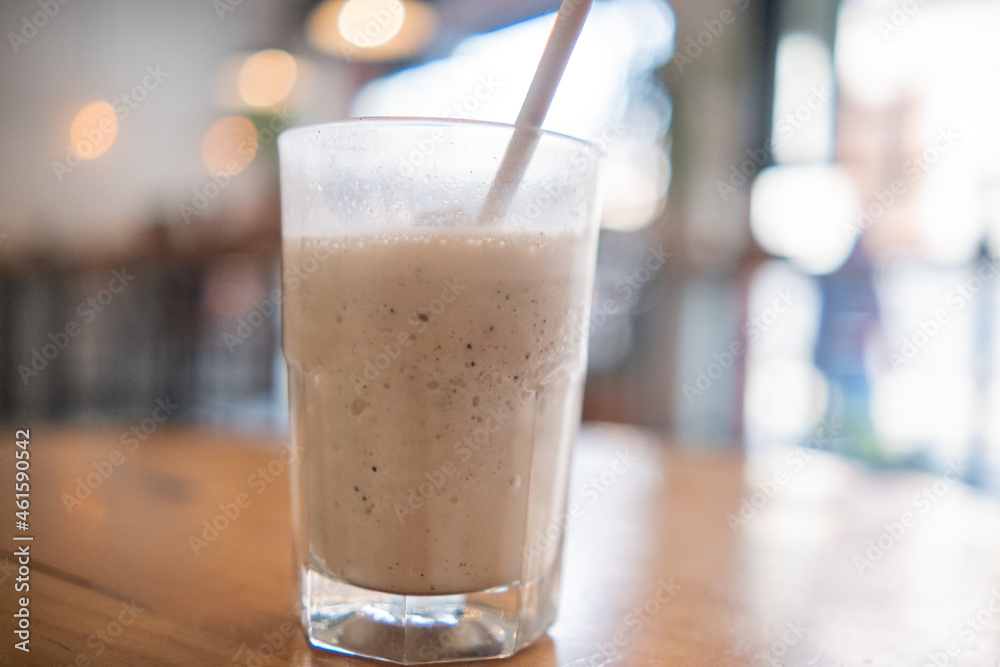 Milkshake with straw in glass above wooden table Milkshake with straw in glass above wooden table
