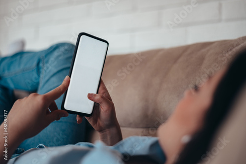 Woman using smartphone while lying on the couch at home