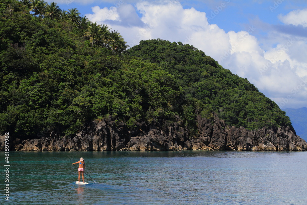 girl paddling an SUP stand up paddle board by herself in a calm tropical ocean. Philippines