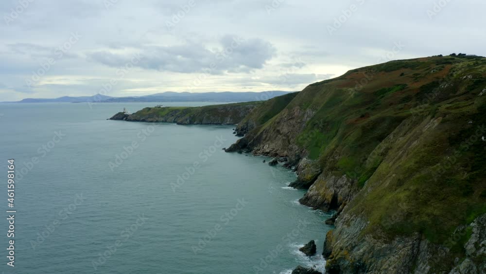 Howth, Dublin, Ireland, September 2021. Drone slowly pushes south along the cliffs at Howth Head towards the Baily Lighthouse with Dún Laoghaire and Killiney in the distance. Howth, Dublin, Ireland, September 2021. Drone slowly pushes south along the cliffs at Howth Head towards the Baily Lighthouse with Dún Laoghaire and Killiney in the distance.