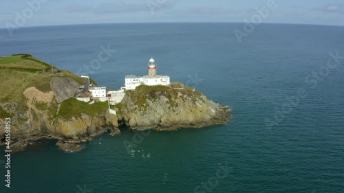 Baily Lighthouse, Howth, Dublin, Ireland, September 2021. Drone gradually orbits while ascending towards the south west lifting up to reveal a wide vista with ships on the Irish sea. photo