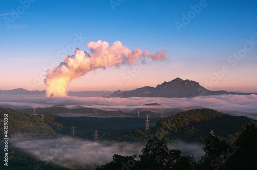 Beautiful sea of fog in the mountains, high voltage pole and steam from the coal power plant in the morning sunrise . Mae moh, Lampang, Thailand. Energy and environment concept . 