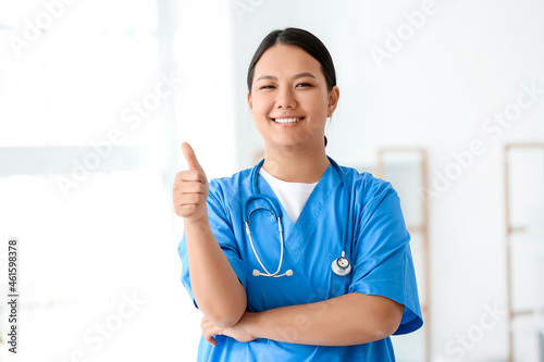 Portrait of female Asian doctor showing thumb-up in clinic
