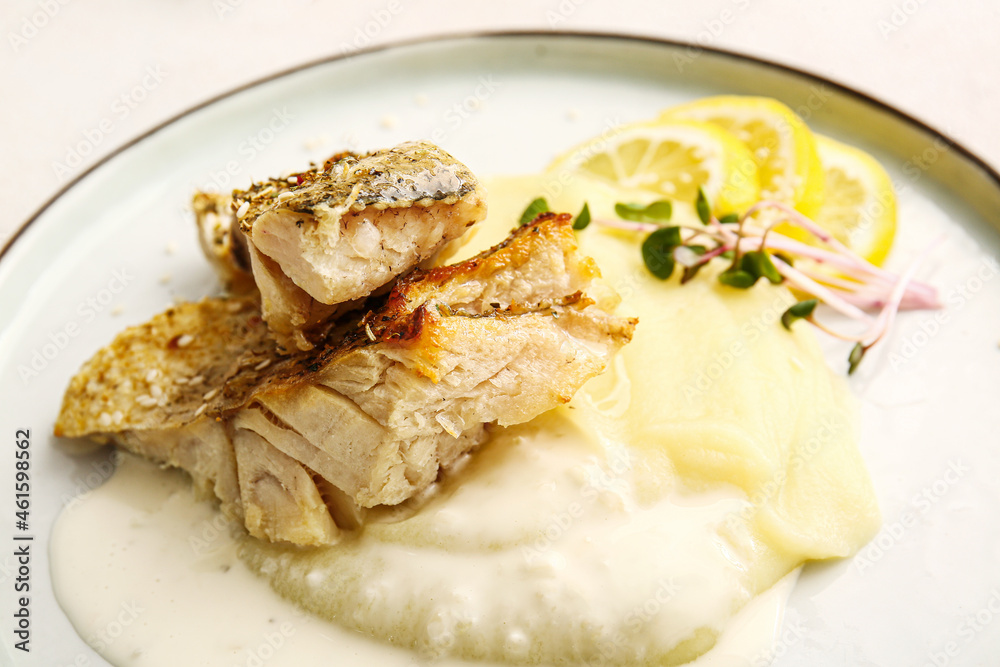 Plate with tasty baked cod fillet, sauce and mashed potatoes on light background, closeup Plate with tasty baked cod fillet, sauce and mashed potatoes on light background, closeup