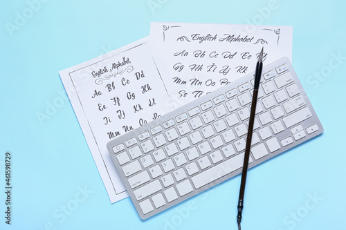Paper sheets with alphabet, computer keyboard and brush on blue background
