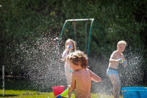 Kids enjoying backyard water fight in summer photo