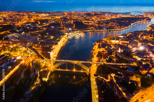Night aerial view of Dom Luis I Bridge over Douro river against backdrop of lighted Porto city, Portugal ..