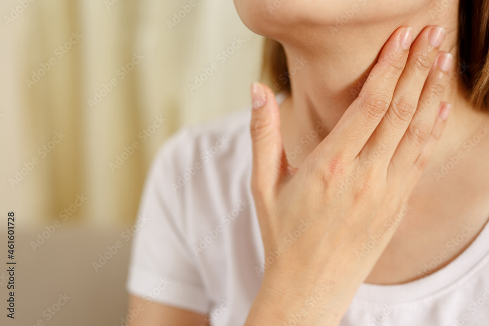 A woman has a sore throat from the flu and COVID-19. A woman has a sore throat from the flu and COVID-19.