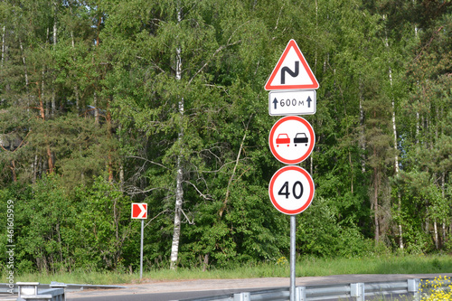 A road sign that limits the speed to 40 km where the winding road is marked with a yellow zigzag sign. There is no overtaking sign.
