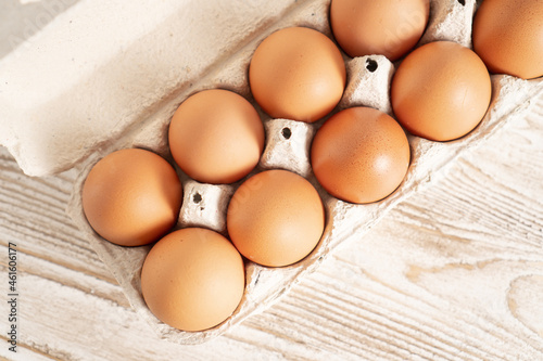 Top view of eggs in the box on the wooden table. Fresh farm egg in carton container on wooden background.