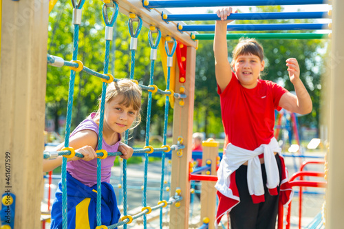 Portraits of positive two teenage girls walking on a playground on a summer day