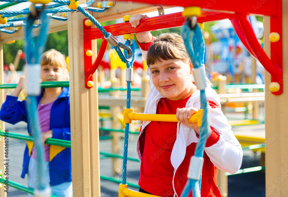 Fototapeta premium Two young girls having good time while playing on outdoor playground.