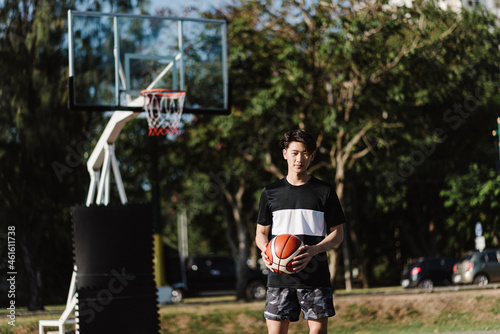 Sports and recreation concept a young male basketball player holding a basketball alone in the basketball court background
