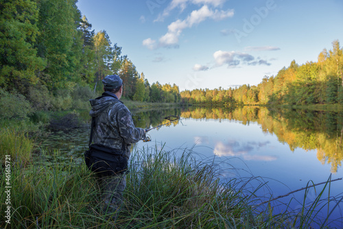 KOSTROMA REGION, RUSSIA - SEPTEMBER 19, 2018: A fisherman with a spinning rod on the shore of a forest lake on a sunny September evening