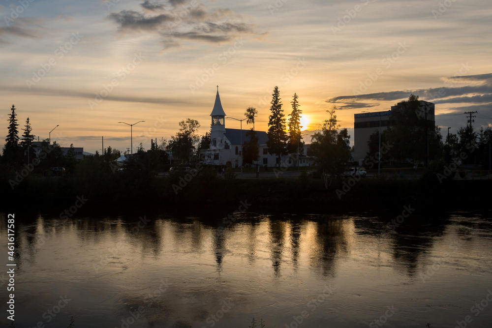 Silhouetted cityscape downtown Fairbanks over Chena river at summer sunset