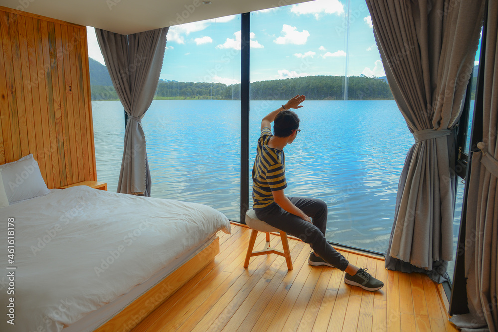 Man enjoying at bed room of wooden lake house