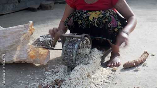 unrecognizable Vietnamese woman striping cassava root in squat down