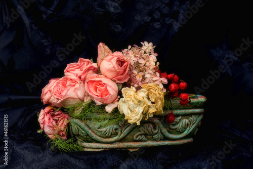 Faded pink and white roses and rose berries with black background