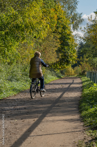 A woman rides a bicycle along the park alley.