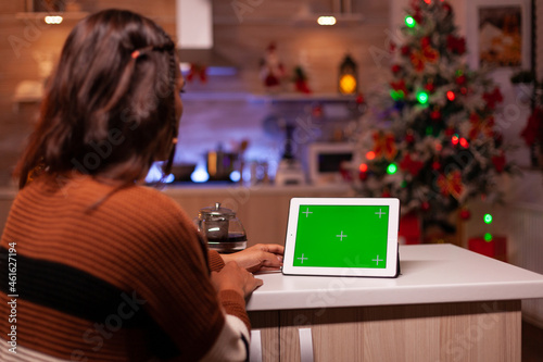Young person watching green screen technology on tablet in kitchen at home. Caucasian woman using digital chroma key concept for background template, mockup gadget app on virtual display