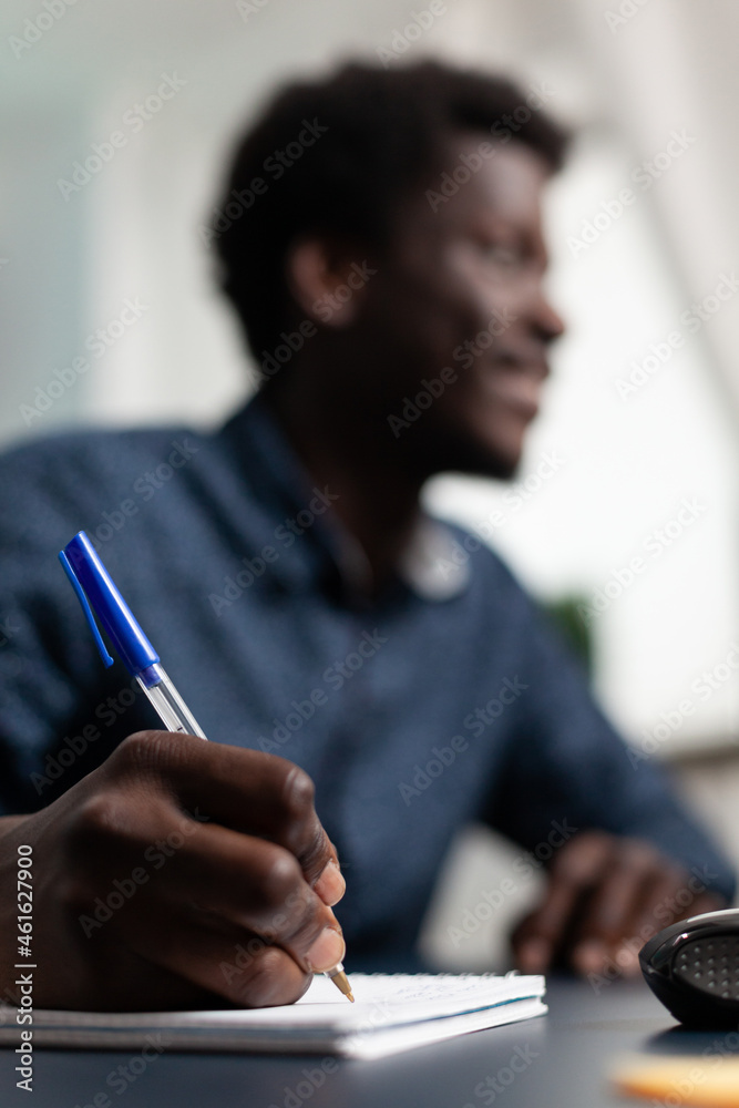 Closeup of black student writing financial strategy on notebook studying business investment at university. Teenager working at management presentation using elearning platform. Computer user at home Closeup of black student writing financial strategy on notebook studying business investment at university. Teenager working at management presentation using elearning platform. Computer user at home