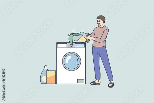Smiling young man near washing machine do laundry wash clothes with soap powder detergent. Happy male perform housework at laundromat. Domestic chores concept. Flat vector illustration. 
