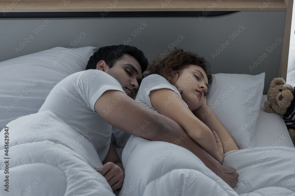 Romantic love couple in duvet lying on the bed in bedroom Romantic love couple in duvet lying on the bed in bedroom