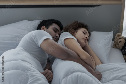 Romantic love couple in duvet lying on the bed in bedroom
