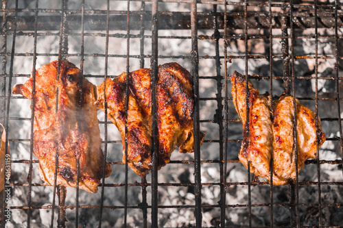 Cooked ruddy chicken meat on a wire rack over a fire. Street food. Picnic in nature. High quality photo
