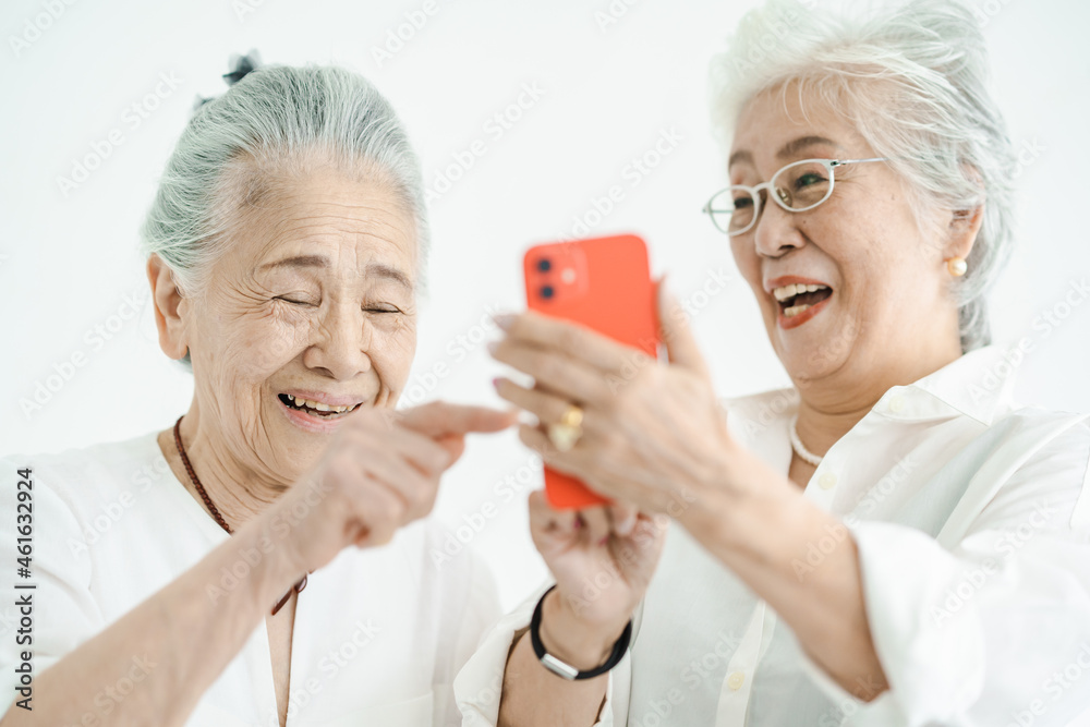 笑顔でスマートフォンの画面を見るシニア女性たち 笑顔でスマートフォンの画面を見るシニア女性たち