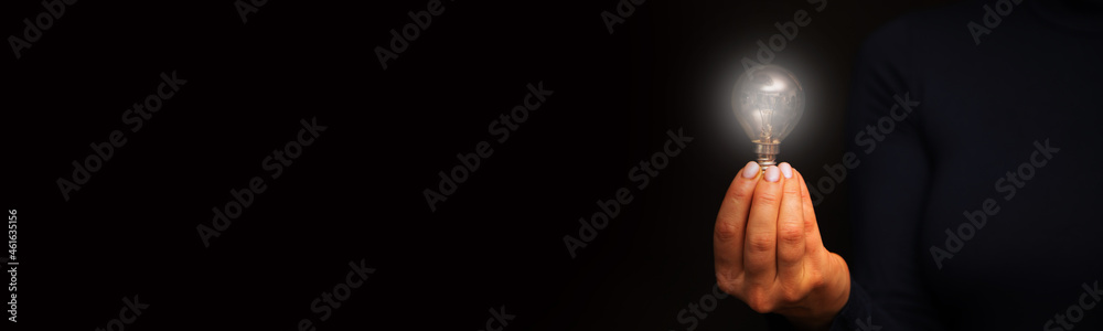 Hand holding a glowing light bulb on the black Hand holding a glowing light bulb on the black