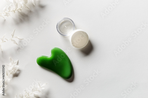 Gouache scrapes from green jade and moisturizing gel, floral decorated. Natural gem stone massager