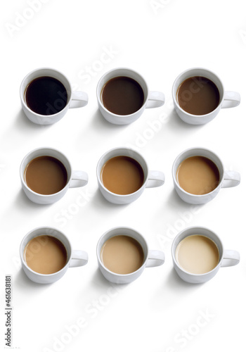 nine mugs with coffee of different colors on a white background photo from above
