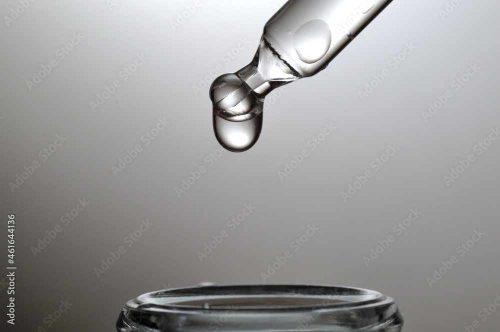 Liquid transparent gel or serum pipette with drops on gray backg