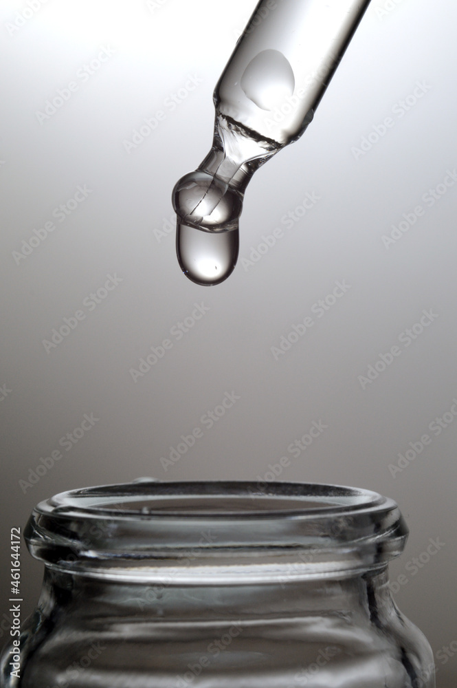 Liquid transparent gel or serum pipette with drops on gray backg Liquid transparent gel or serum pipette with drops on gray backg