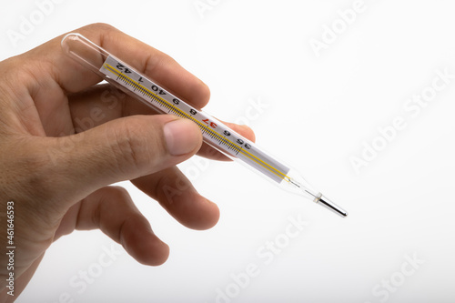 Left hand holding a thermometer on white background