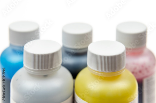 Five plastic bottles with different inks for ink-jet printer on a light background
